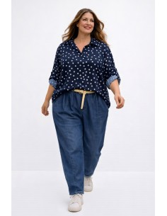 Mujer curvy sonriendo con blusa azul marino de lunares en tallas grandes y vaqueros baggy