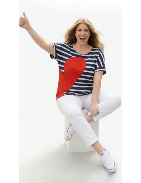 Mujer curvy con camiseta marinera corazón rojo y pantalón blanco.